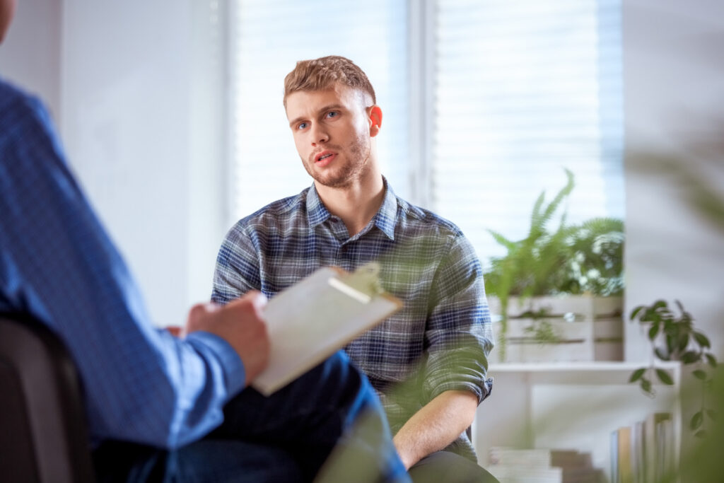 Student sharing problems with therapist University student sharing his problems with therapist. Young male is sitting with mental health professional. They are in lecture hall.